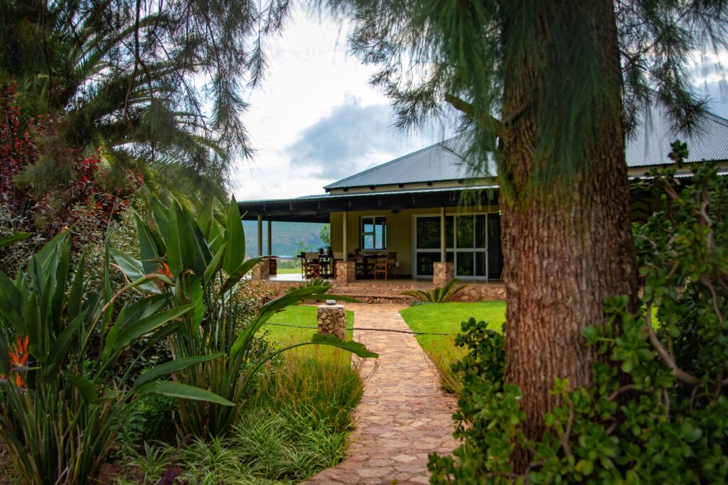 A scenic garden path leads to a charming country house under a cloudy sky.